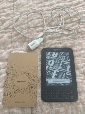 Amazon Kindle E-reader in Black with White Charger and Tan Quick Start Guide